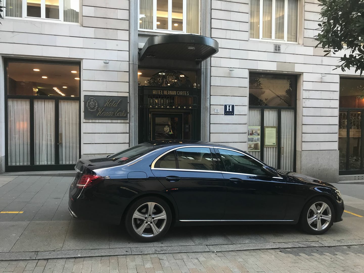 Alquiler de vehículos con conductor en Madrid - Coche negro frente al Hotel Hernán Cortés