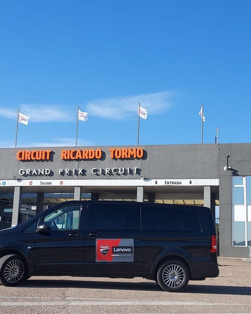 Alquiler de vehículos con conductor en Madrid - Furgoneta negra con cartel publicitario de Lenovo frente al Circuito Ricardo Tormo